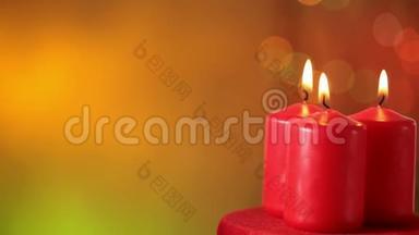 三支燃烧的圣诞蜡烛在暖色模糊的圣诞背景下旋转